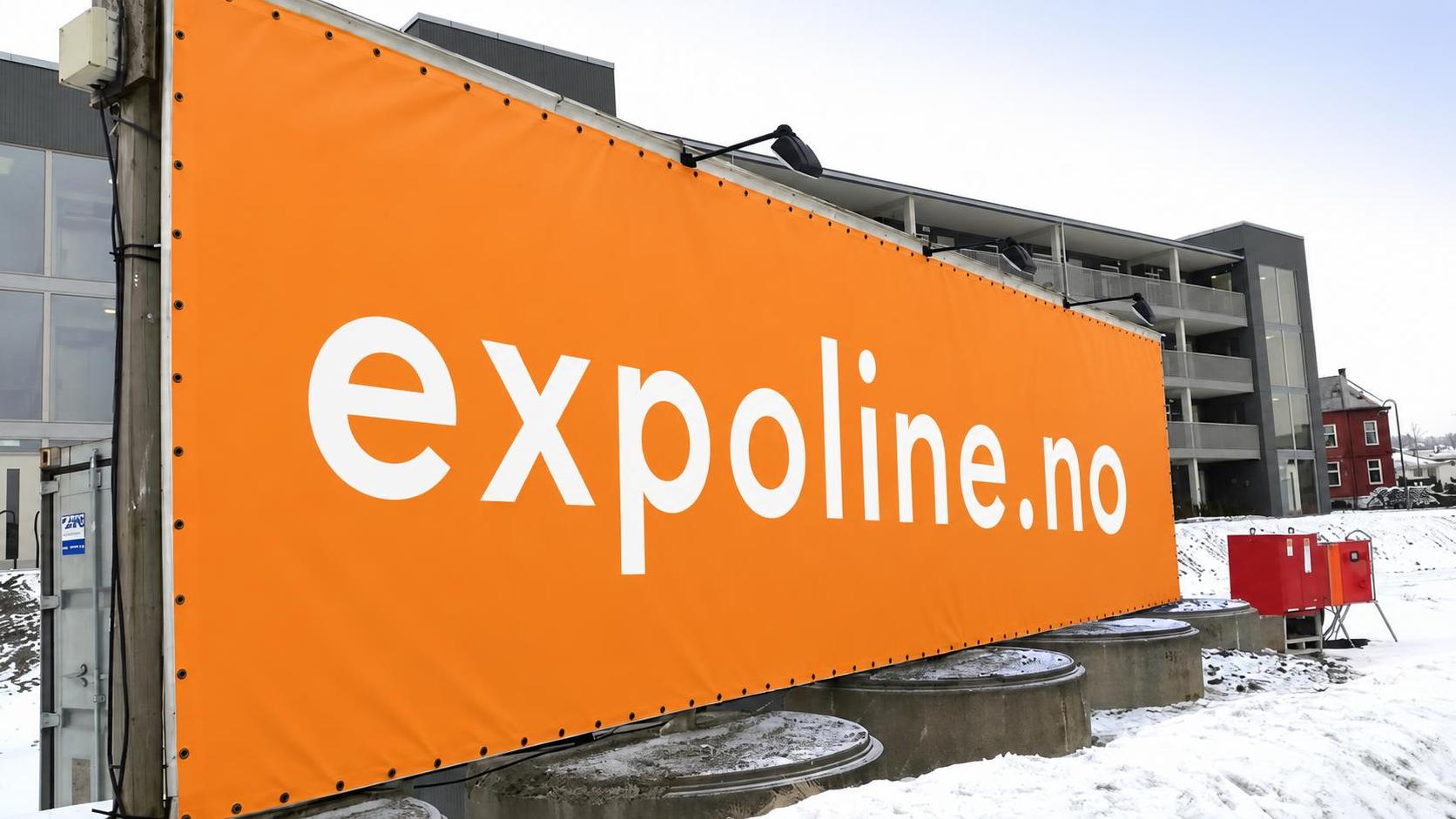 Mesh-banner med trykk montert på byggegjerde ved siden av PVC-banner på fasade